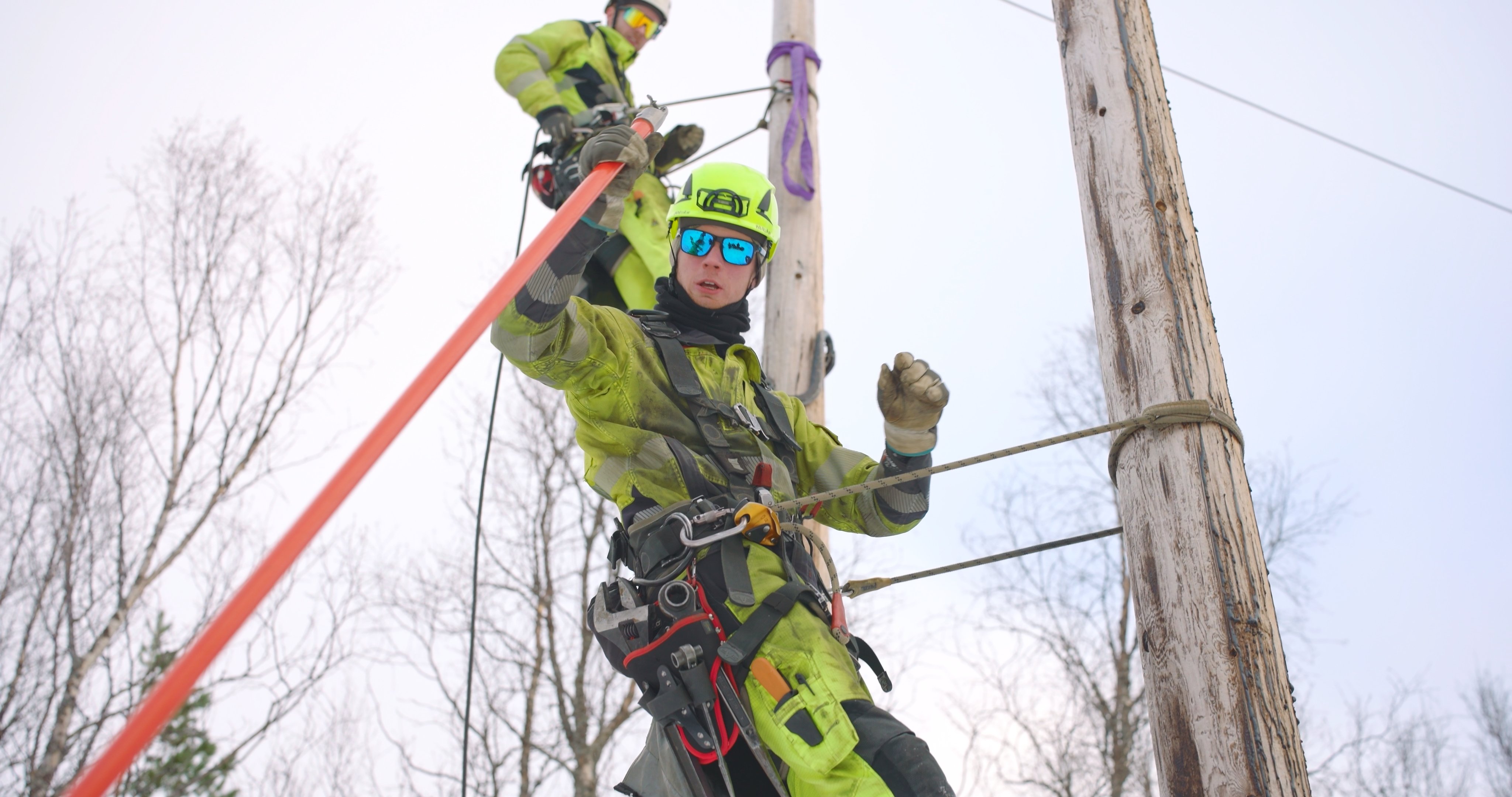 En energimontør fra Nettpartner Troms henger fra en mast